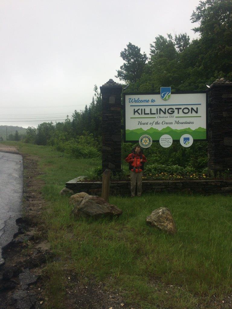 Self-explanatory posing-by-road-sign photograph.